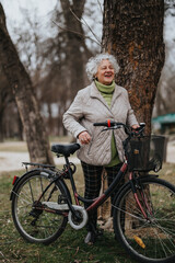 A mature woman enjoying outdoor activities, standing with her bicycle in a serene park environment.