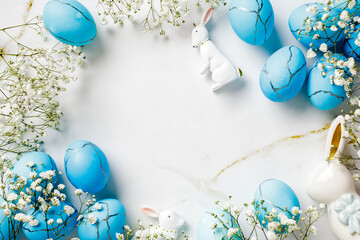Blue and white Easter egg arrangement with a white rabbit and a blue egg. The eggs are scattered around the rabbit and the arrangement is on a marble countertop