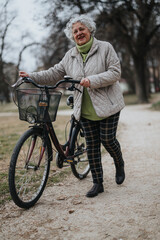 Mature woman holding her bicycle, preparing for a ride along a serene park path, depicting an active lifestyle