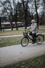Fototapeta premium A mature woman, enjoying retirement by riding her bicycle through a serene park setting