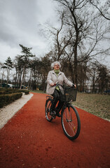 Obraz premium Mature female retiree outdoors with her bicycle on a scenic park pathway, exemplifying an active lifestyle and leisure activity.