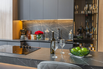 wood decorated dark kitchen area with coocking island in huge modern spacious apartment with high loft style ceilings, wooden decoration and grey walls