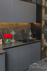 wood decorated dark kitchen area with coocking island in huge modern spacious apartment with high loft style ceilings, wooden decoration and grey walls