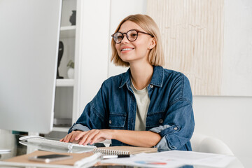 Happy smiley caucasian woman working remotely on computer at home desk. Young freelancer student...