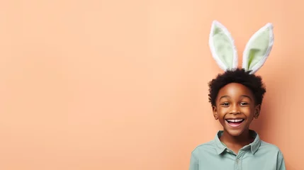 Fotobehang black boy with bunny ears smiling on studio background © Spyrydon