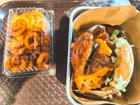 A tray with a delicious Juicy gourmet Burger and curly fries.
