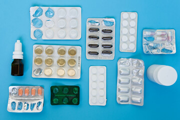 Group of different pills and tablets plastic blisters, drop bottle, plastic pill box spaced on a blue background. Healthcare and medicine concept. Advertising or presentation purposes