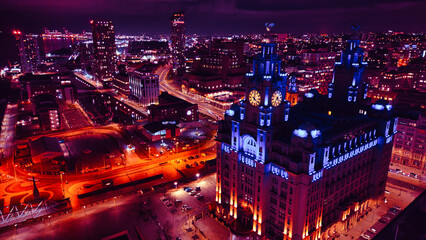 Aerial night view of a vibrant cityscape with illuminated streets and an iconic building in Liverpool, UK.