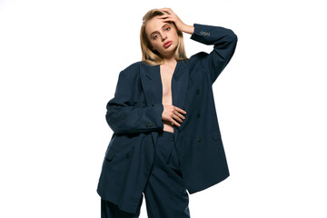alluring sexy woman with blonde hair in black unbuttoned suit on white backdrop looking at camera