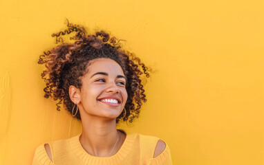Joyful young woman, vibrant yellow backdrop, epitomizing positivity and energy in a professional light