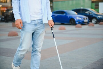 Blind man close-up with a walking stick. Walking down the street