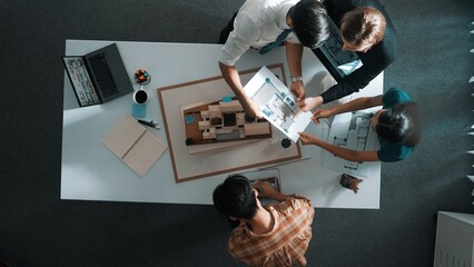 Top down view of manager pointing at house model and explain building design. Aerial view of architect engineer brainstorming about interior construction while tablet display house plan. Alimentation. - obrazy, fototapety, plakaty