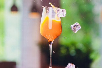 ice cubes falling into a splashing orange cocktail.