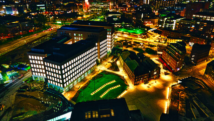 Aerial night view of an illuminated urban landscape with buildings and streets in Leeds, UK.