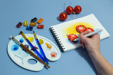watercolor painting of red balls. Winter watercolor painting with a set of watercolor paints and paintbrushes. Top view