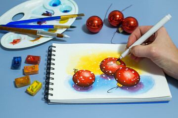 watercolor painting of red balls. Winter watercolor painting with a set of watercolor paints and paintbrushes. Top view