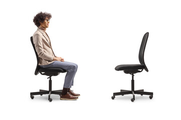 Profile shot of a man sitting in an office chair and looking at an empty chair