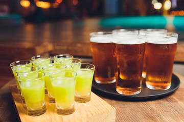 Multicolour alcoholic shots on wooden tray in nightclub.