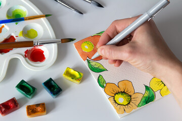 watercolor painting of card with flowers , artist's hand, top view