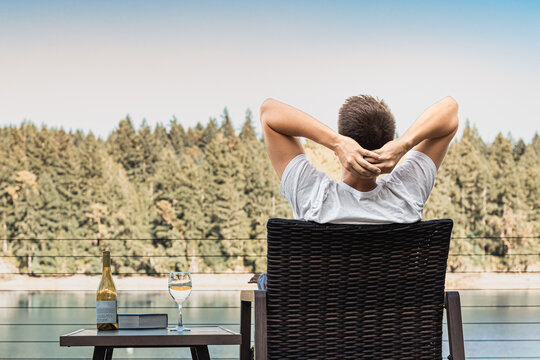 Happy carefree man sitting by a lake sitting back enjoying the beautiful nature view 