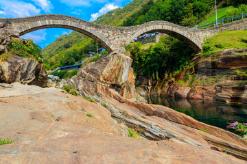 Fototapeta na wymiar Ancient double arch stone Roman bridge (Ponte dei Salti) over the clear water of the Verzasca river in Lavertezzo ,Verzasca Valley, Ticino Canton, Switzerland