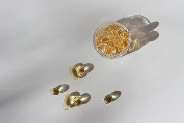 transparent jar of fish fat oil Omega-3 capsules on white background with hard shadow and copy space. vitamins, pharmacy and supplements concept. top view