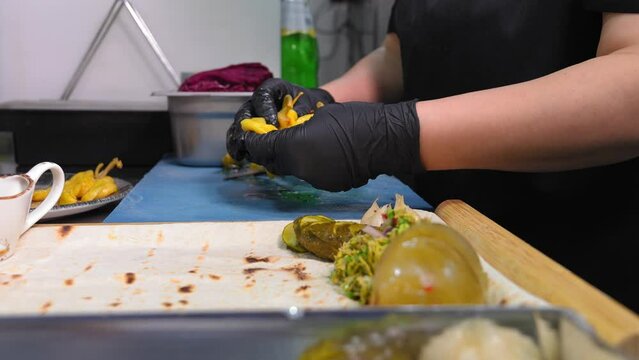 Chef Paovar in kitchen of restaurant collects assorted on plate of pita bread with pickles, cabbage, garlic, restaurant menu Assorted pickled or pickled vegetables.