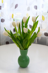 White tulips in a vase on a white table. - 756002953