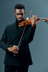 African American Man in Black Suit Playing Violin with Passion on Gray Background in Studio Setting