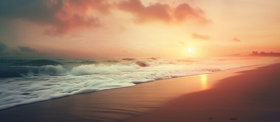 A hazy image of a beach at sunset with the sun peaking through the clouds, creating a mesmerizing atmosphere over the fluid water and natural landscape