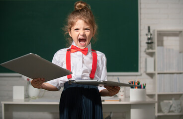 Bad angry school girl vs distance education. Sad kid broken online laptop at school. Smashing...