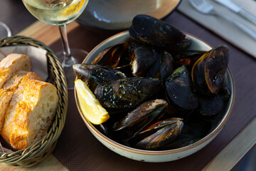 Delicious steamed mussels with green sauce served in bowl
