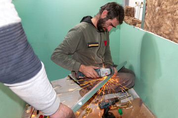 A mature  experienced worker using a grinder to install a drywall profile. Home renovation workers...