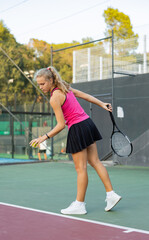 Caucasian young woman in tank top and skirt playing tennis match during training on court.