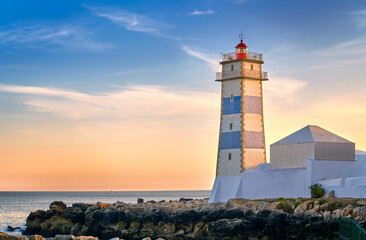 Fototapeta na wymiar Beautiful sunset on sea shore and Santa Marta lighthouse in Cascais