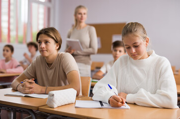 Fototapeta na wymiar Pupils write in notebooks while sitting at desks in a school class