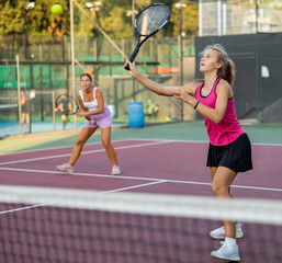 Young woman in skirt playing tennis on court. Racket sport training outdoors.