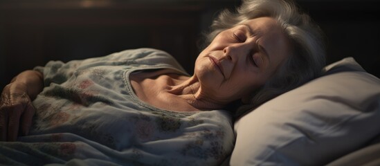 The elderly woman lays in bed, peacefully asleep with a pillow under her head. In the darkness, she finds comfort and serenity, a peaceful event in her day