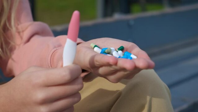 Pregnancy test and abortion pills. A pensive teen girl hold abortion pills and unwanted pregnancy test on the bench during day time.