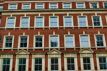 Fototapeta na wymiar Facade of a classic red brick building with symmetrical windows against a clear sky in Leeds, UK.