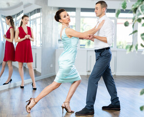In spacious choreography studio, confident woman professional tango instructor and male student...