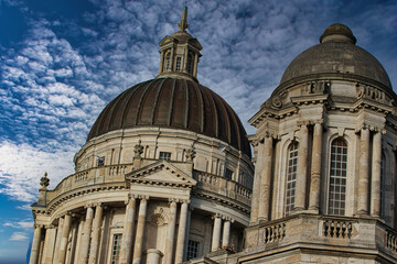Dramatic view of historic domed buildings against a cloudy blue sky in Liverpool, UK.