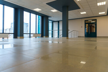 An empty spacious room of a modern office building with large windows. An empty hall with columns...