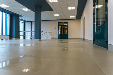 An empty space with railings and large windows. The modern interior of the lobby of the office building. A lighted long corridor in a modern business center