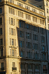 Fototapeta na wymiar Sunlight casting shadows on a classic urban building facade during golden hour, highlighting architectural details in Liverpool, UK.