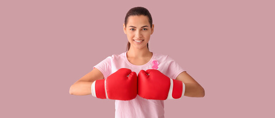 Beautiful woman with pink ribbon and boxing gloves on color background. Breast cancer concept