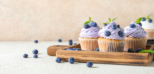 Wooden board of delicious cupcakes with blueberries and mint on white background - Powered by Adobe