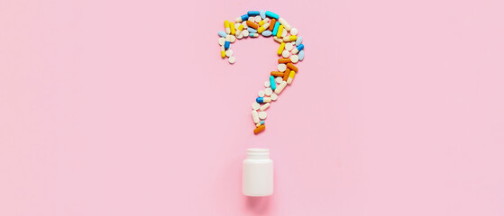 Question mark made of different pills and jar on pink background