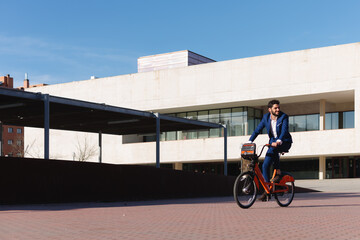 Copy space of modern building with a man in formalwear riding a bike.