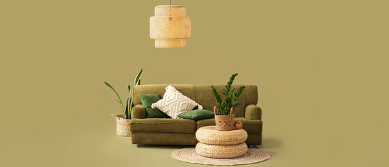 Cozy sofa, wicker poufs and houseplants on green background